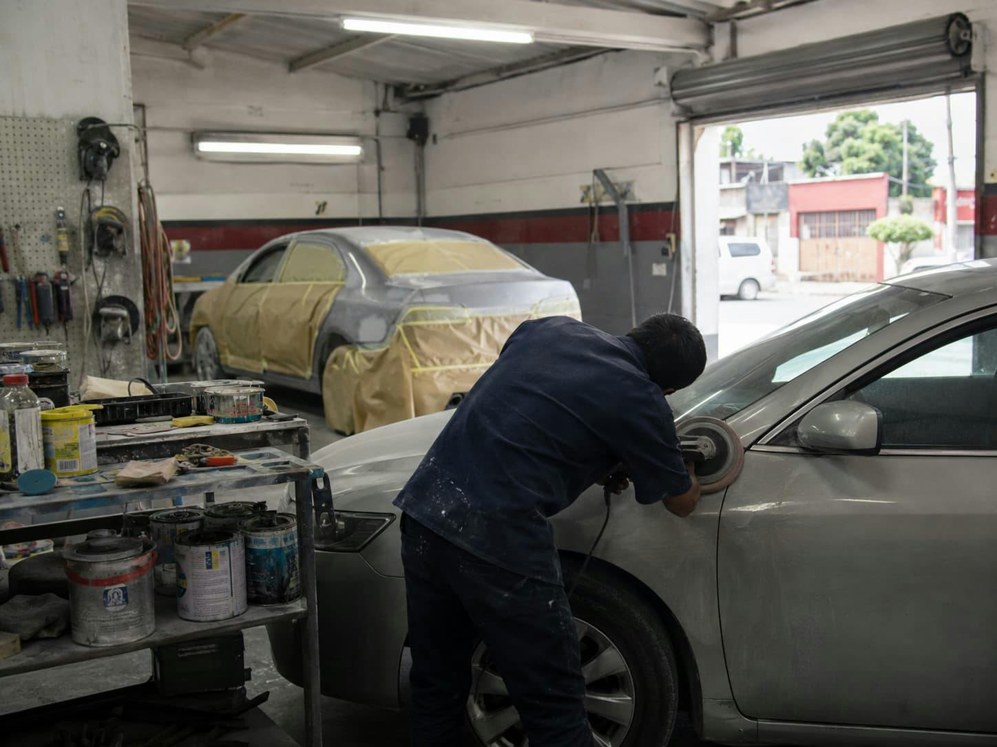 Mexican mechanic repairing a car at an auto body shop